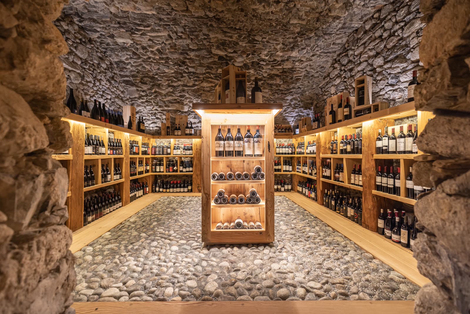 A vaulted stone wine cellar lined with bottles